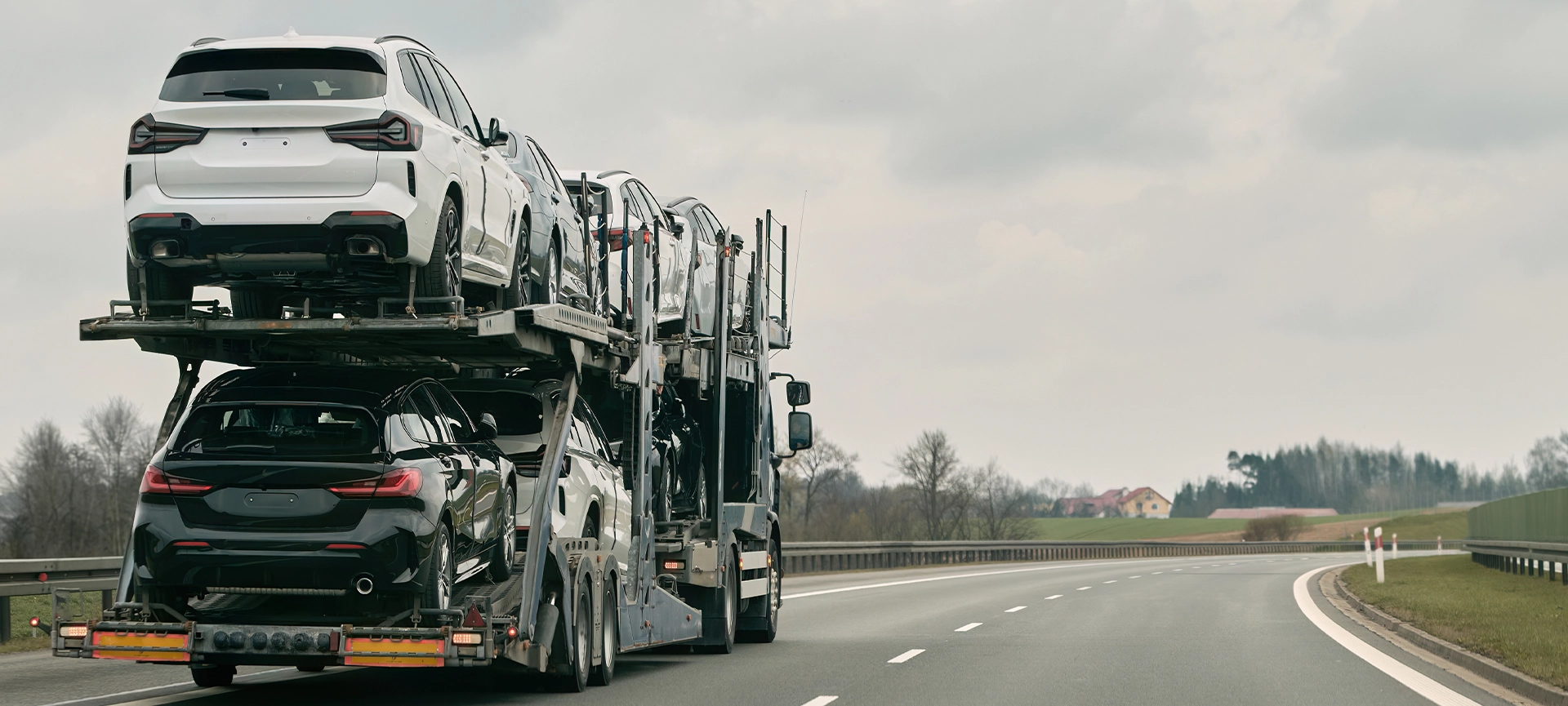 car transporter carries new luxury vehicles along the highway, back view of the trailer